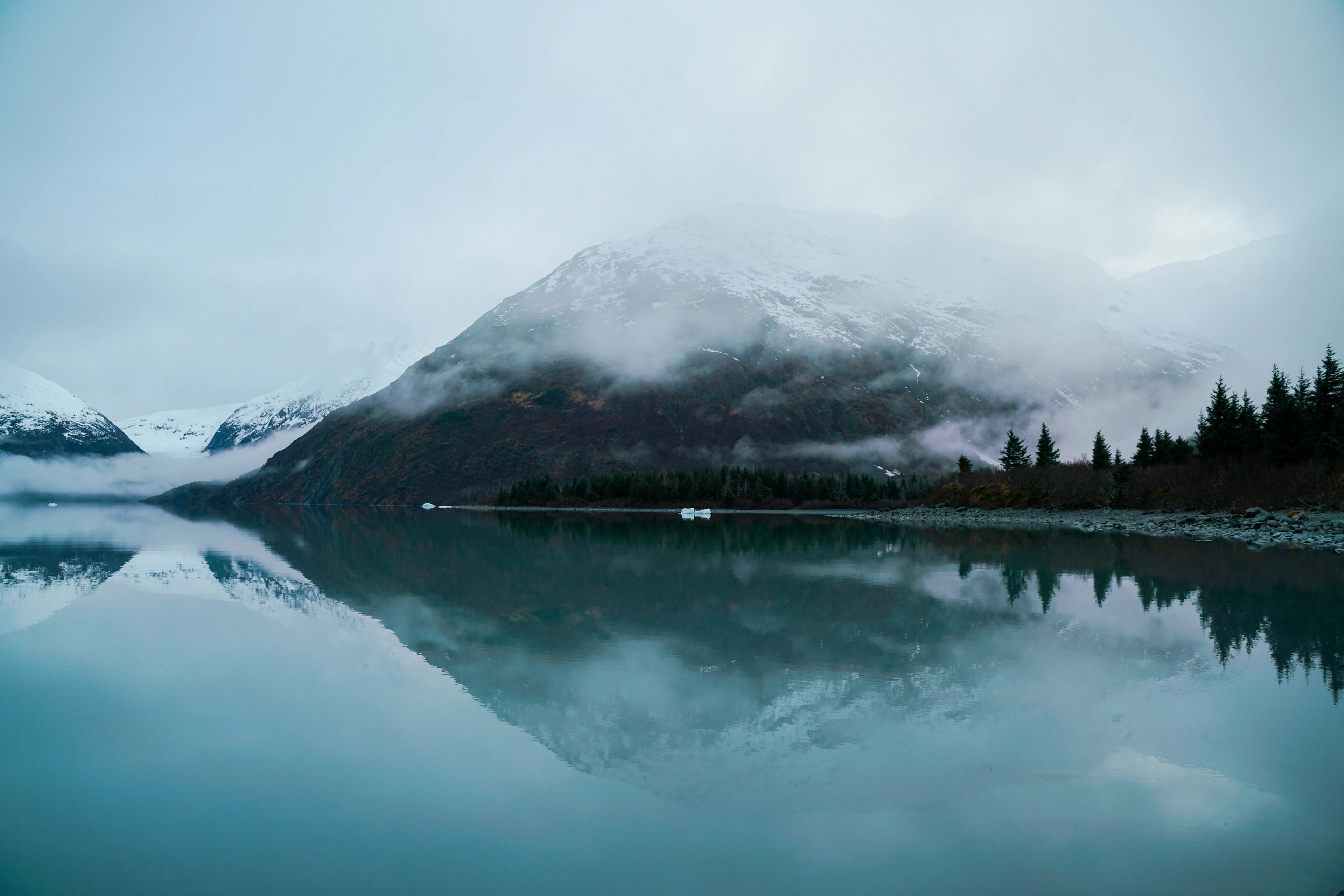 Snow-covered mountains, evergreen forest and a still lake in Alaska